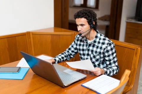 Guy using headset and laptop computer, chatting on Internet Foto stock