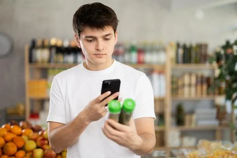 Guy using smartphone to scan herbal spices in supermarket Stock-Fotos
