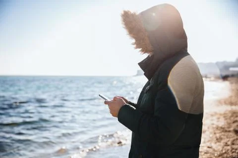 Guy using smartphone while standing on the beach Stock Photos