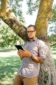 Guy using tablet pc in summer park. Stock Photos