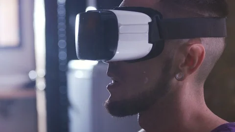 Guy in VR glasses looking straight, speaking. Young Caucasian man sharing Stock Footage 98169816