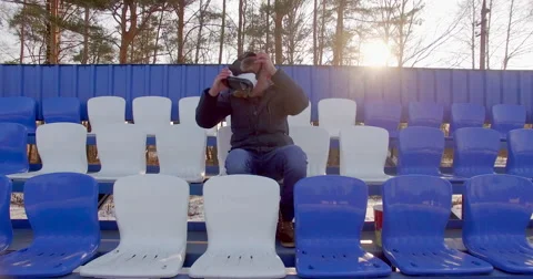 A guy in VR glasses sitting at the stadium Stock Footage 62679869
