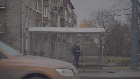 THE GUY IS WAITING FOR THE BUS AT THE BUS STOP Stock Footage 124730929