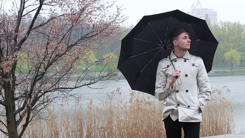 A guy is waiting for a girlfriend in the rain Stock Footage 74852889