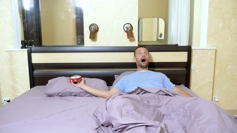 The guy wakes up in the morning and gets angry that he overslept. looking at the Stock Footage 111495074