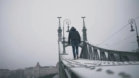 The guy is walking along the iron beam of a huge bridge Vídeos de archivo 76615500
