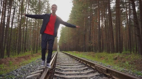 The guy is walking along the rails in the middle of the forest. Stock Footage 93975331