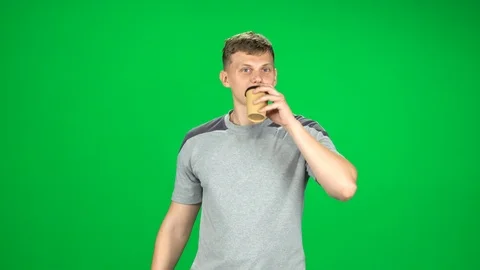 Guy is walking and drinking disgusting coffee from a paper cup. Chroma Key Stock Footage 120310548