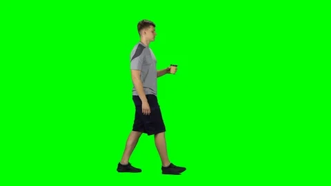 Guy is walking and drinking disgusting coffee from a paper cup. Chroma Key Stock Footage 123560384