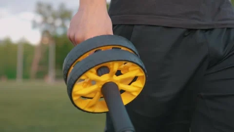 Guy walking around the stadium with abdominal rollerr in his hands abdominal Video stock 260829435