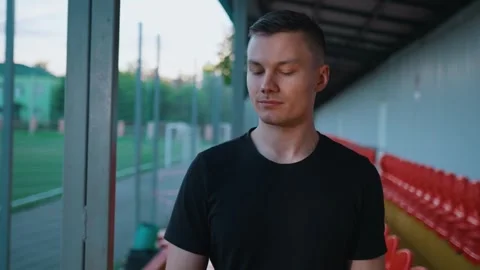 Guy walking around the stadium with wrist expander in his hands Video stock 260829472