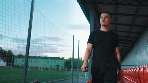 Guy walking around the stadium with wrist expander in his hands Stock Footage 260829508