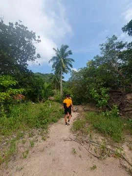 Guy walking on a dirt path with palm trees around in Koh Tao island, Thailand Stock Photos