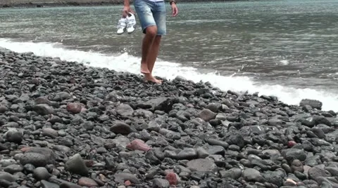 A guy walking in the gravel on the beach (return) Stock Footage 20510979