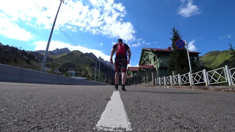 The guy is walking in a mountainous area on road. Vídeos de archivo 152472621