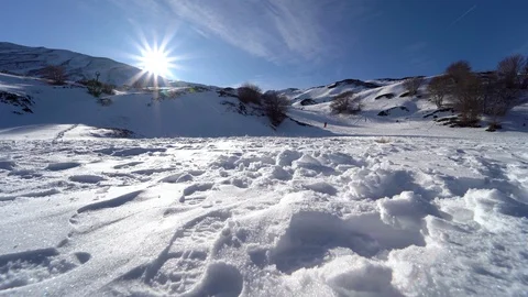 Guy walking in the snow with the sun on his face, footprint in the snow Video stock 122320077