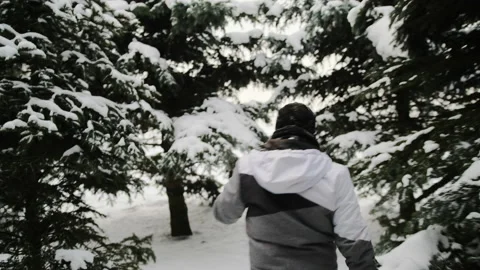 The guy is walking in a snowy forest between fluffy green fir trees Video stock 149315477