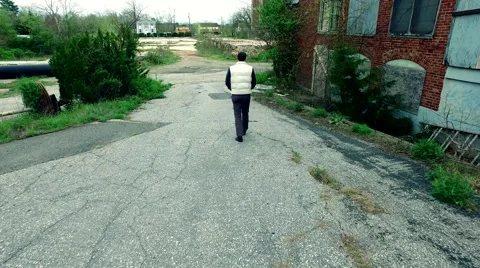 Guy Walking Through the Ruins of an Abandoned Factory Stock Footage 62927829