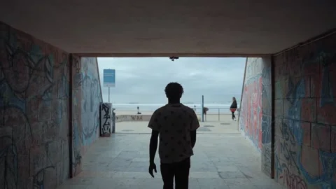 A guy walking through a tunnel to the beach Video stock 202134346