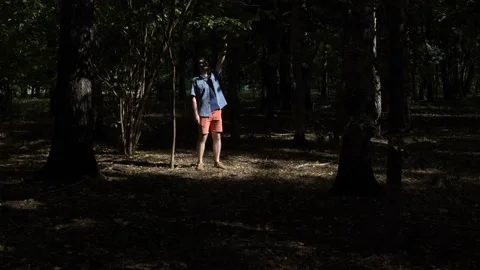 Guy is walking in the woods. Covers his face with his hand from the sun Stock Footage 139142891
