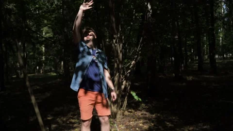 Guy is walking in the woods. Covers his face with his hand from the sun Stock Footage 139143355
