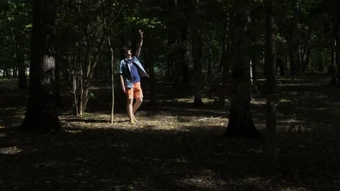 Guy is walking in the woods. Covers his face with his hand from the sun Stock Footage 139143405