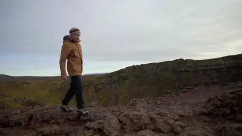 A guy walks along the edge of a cliff of a volcano. Extreme steps along the edge Stock Footage 130442348