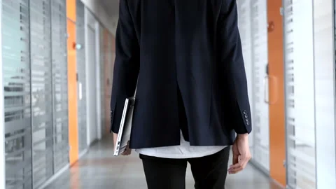 The guy walks along the narrow corridor of the office, holding a laptop. Young Stockbeeldmateriaal 162192162