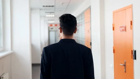 The guy walks along the narrow corridor of the office, holding a laptop. Young 스톡 동영상 162192504