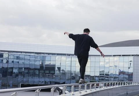 The guy walks along the railing at a height. Stock Photos