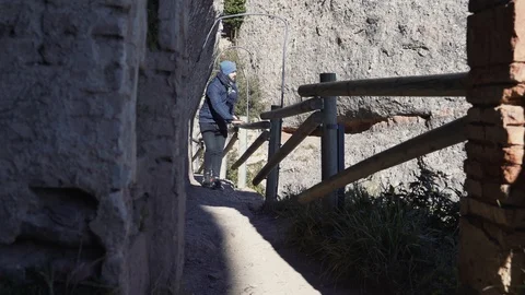 A guy walks on the edge of a steep mountain slope leaning on the railing Stock Footage 101270389