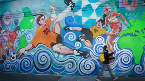 Guy walks by mural with ball Stock Footage 37065763