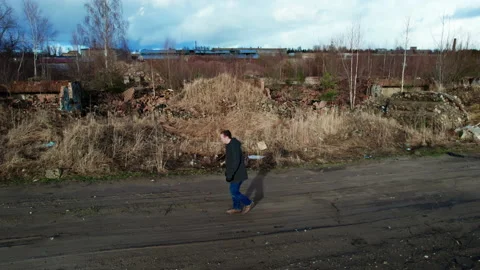 Guy walks parallel to camera, walks and smiles. around ruins, guy is glad Stock-Footage 171837296