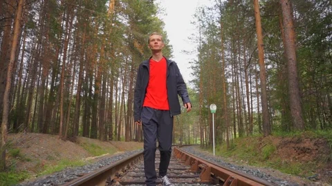 A guy walks by rail among the forest towards the camera. Stock Footage 93975267