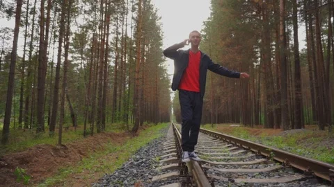The guy walks on the rails and talks on the phone. Stock Footage 93975365