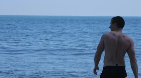 Guy walks into the sea to swim Stock Footage 64832969