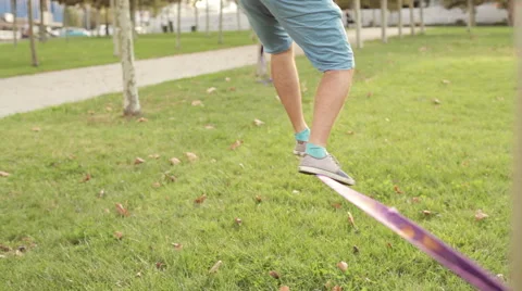 Guy walks on slackline at public park Stock Footage 68407776