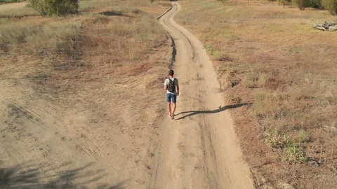 The guy walks the steppe road burnt by the sun Stock Footage 107855036