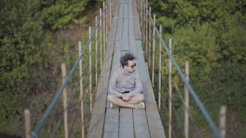 Guy walks on suspended bridge in the forest Stock Footage 139016170
