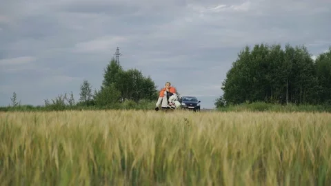A guy walks through a field of wheat with things that he carries on himself Stock Footage 158127169