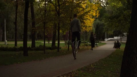 Guy walks through the park on stilts on springs Jollyjumper Stock Footage 143469315