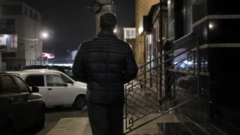 Guy in warm black jacket walks on paved sidewalk in street Stock Footage 145712941