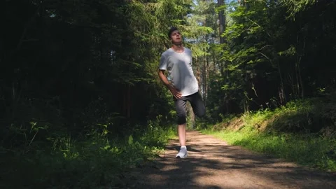 Guy is warming-up in the forest, stretching his muscles before running. Stock Footage 157071758
