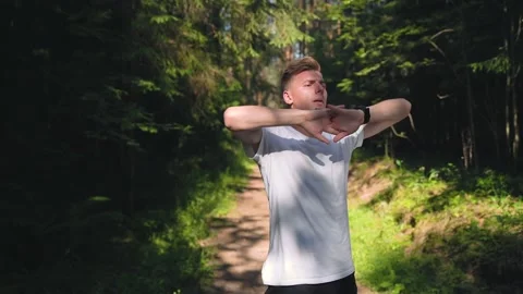 Guy is warming-up in the forest, stretching his muscles before jogging. 4K Video stock 157071769