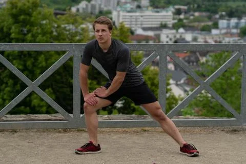 The guy warming up before training with a beautiful view of the city in Germany Stock Photos