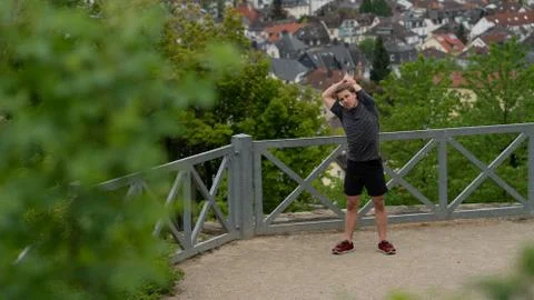 The guy warming up before training with a beautiful view of the city in Germany Stock Photos