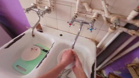 The guy washes dirty dishes, plates and spoons with water. 動画素材 332286714