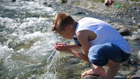 The guy washes himself cold mountain water.Early morning traveller. Stock Photos