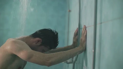 The guy washes in the shower after training, water flows from the tap, he is Stock Footage 138634582