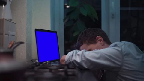 Guy watching at blue key notebook computer display at kitchen near stove Video stock 83253547